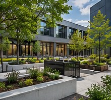 Courtyard with raised concrete planters and ornamental grasses outside a glass office building