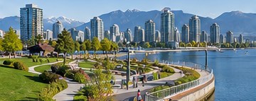Curving seawall path through a waterfront park with lawns and downtown towers across the water